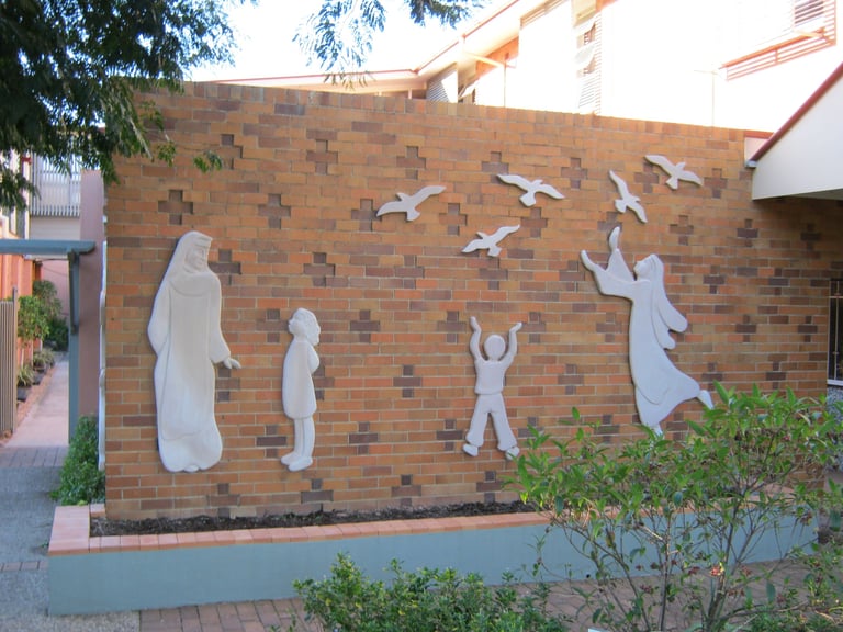White silhouette mural on brick wall depicting figures of different heights with birds in flight above them