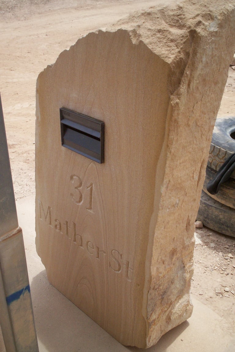 Carved stone mailbox with number 31 and text, featuring a dark metal mail slot on light tan stone