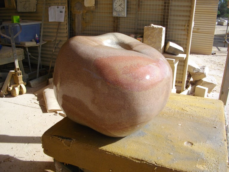 Large terracotta ceramic sculpture with curved, organic shape sits on yellow wooden platform in pottery studio workshop