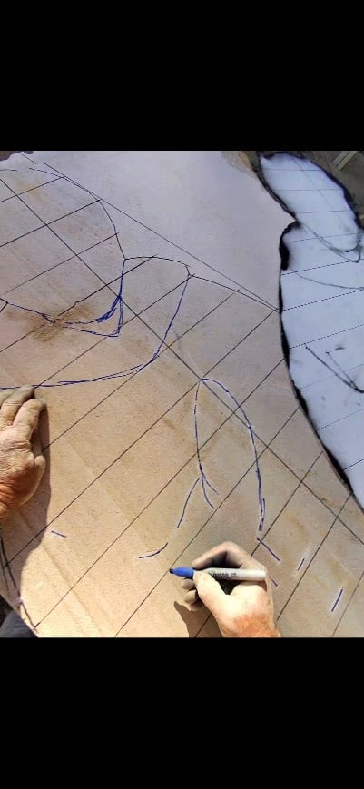 Person drawing architectural floor plan with pencil on paper, showing grid lines and layout design