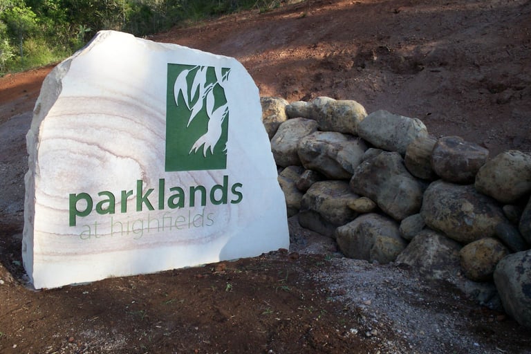 Parklands branded white banner or tarp displayed on soil next to stacked concrete blocks or timber debris on bare ground