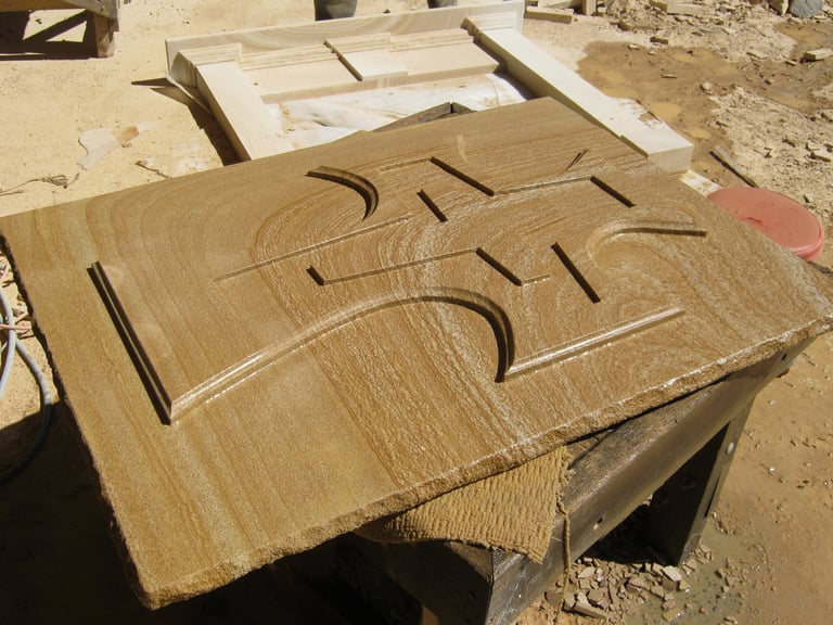 Wooden panels with decorative curved relief cuts laid on an outdoor work surface surrounded by construction materials
