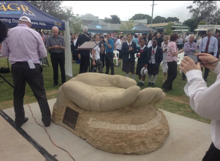 Crowd gathers around a large sculptural hat display at an outdoor agricultural or community event