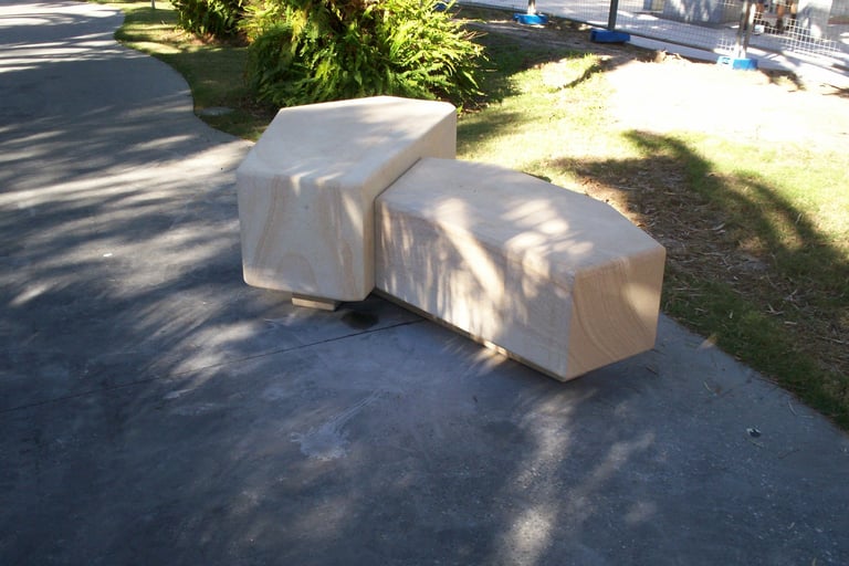 Two white canvas-covered furniture pieces sit on a driveway with green lawn and trees in background on a sunny day